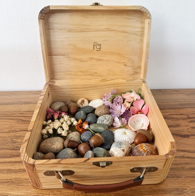 Wooden box with decorative stones and flowers on a wooden surface